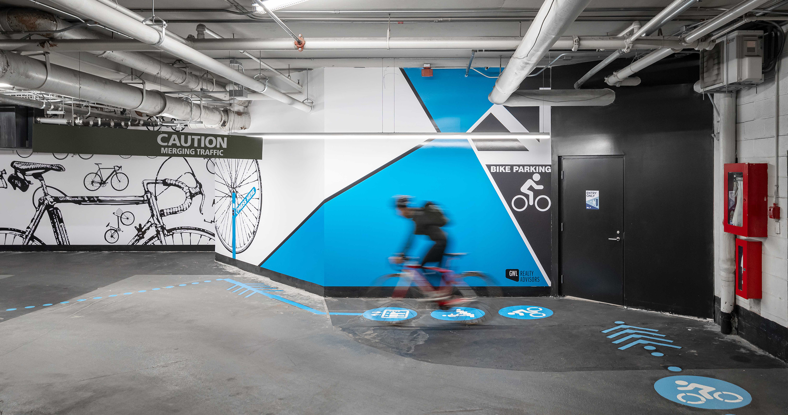 A bicyclist cycles into the bike amenities area, following bold graphics to ensure safe wayfinding