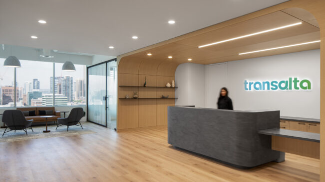 Curved wood reception area with a stone desk adjacent seating area and meeting room